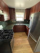 Unit 2 Kitchen with appliances with stainless steel finishes, pendant lighting, tasteful backsplash, sink, and light wood-type flooring