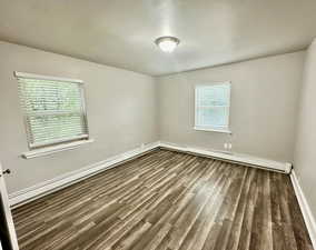 Unit 3 bedroom #1 with a baseboard radiator, dark wood-type flooring, and a wealth of natural light