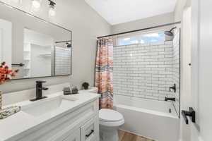 Full bathroom featuring vanity, wood-type flooring, shower / bath combo, and toilet