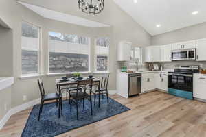 Kitchen featuring appliances with stainless steel finishes, sink, white cabinets, and light wood-type flooring