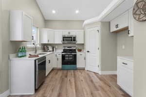 Kitchen featuring white cabinetry, sink, stainless steel appliances, and light wood-type flooring