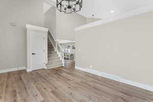 Unfurnished living room featuring high vaulted ceiling, light hardwood / wood-style floors, and a notable chandelier