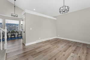 Dining space with an inviting chandelier, vaulted ceiling, and light hardwood / wood-style flooring