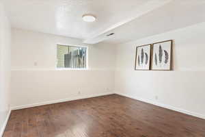 Unfurnished room featuring a textured ceiling and dark hardwood / wood-style flooring