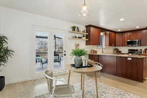 Kitchen featuring hanging light fixtures, light hardwood / wood-style flooring, kitchen peninsula, and appliances with stainless steel finishes