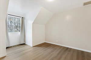 Bonus room with vaulted ceiling and light hardwood / wood-style floors