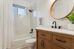 Full bathroom featuring vanity, shower / bath combination with curtain, and toilet