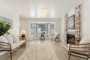 Living area with a brick fireplace and light hardwood / wood-style flooring