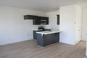 Kitchen featuring sink, a breakfast bar area, appliances with stainless steel finishes, kitchen peninsula, and light hardwood / wood-style floors