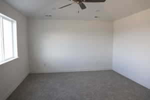 Carpeted spare room featuring lofted ceiling and ceiling fan