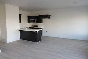 Kitchen with appliances with stainless steel finishes, sink, a breakfast bar area, kitchen peninsula, and light wood-type flooring