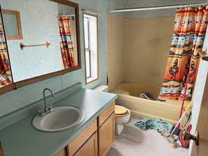 Full bathroom with vanity, shower / bath combination with curtain, and toilet