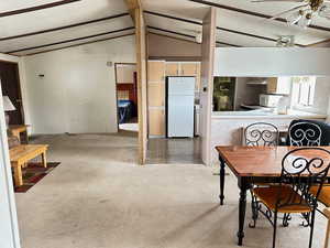 Carpeted dining area featuring lofted ceiling with beams and a textured ceiling