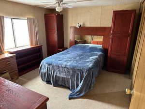 Bedroom with ceiling fan, carpet floors, and a textured ceiling