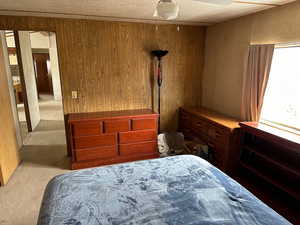 Carpeted bedroom with a textured ceiling and wooden walls