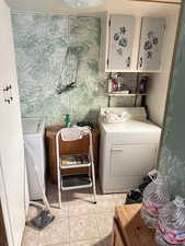 Laundry area with cabinets and light tile patterned floors