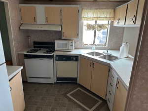 Kitchen featuring light brown cabinetry, sink, white appliances, and backsplash