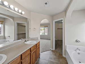 Master Bathroom featuring a tub to relax in, vanity, and tile patterned floors