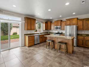 Kitchen featuring sink, a breakfast bar area, a kitchen island, stainless steel appliances, and stone countertops