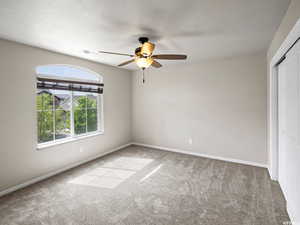 Master Bedroom with ceiling fan, light carpet, and a closet