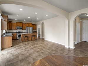 Entertainment Kitchen with sink, a breakfast bar, stainless steel appliances, a center island, and dark stone counters