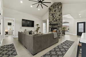 Living room featuring a stone fireplace, high vaulted ceiling, and light hardwood / wood-style floors