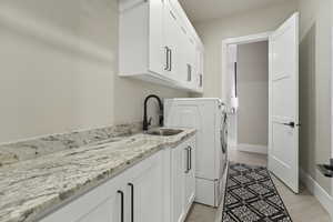 Clothes washing area featuring sink and cabinets