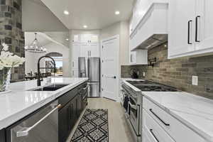 Kitchen with sink, decorative light fixtures, premium appliances, custom range hood, and white cabinets, quartz countertops