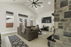 Living room featuring high vaulted ceiling, french doors, ceiling fan, and light wood-type flooring