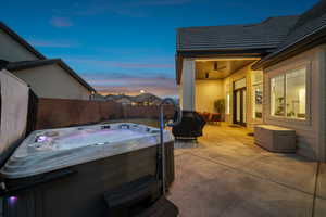 Patio terrace at dusk featuring a hot tub