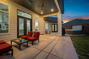 Patio terrace at dusk featuring french doors, ceiling fan, and a hot tub