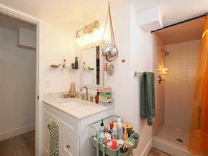 Bathroom featuring hardwood / wood-style flooring, vanity, and a tile shower