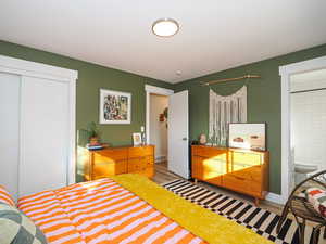 Bedroom featuring wood-type flooring, connected bathroom, and a closet