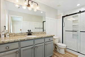 Bathroom with vanity, hardwood / wood-style floors, an enclosed shower, and toilet