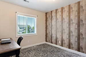 Unfurnished office featuring wooden walls and a textured ceiling