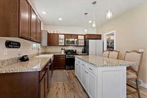 Kitchen featuring a kitchen island, appliances with stainless steel finishes, a breakfast bar, pendant lighting, and sink