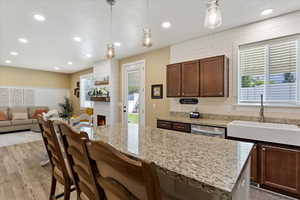 Kitchen featuring pendant lighting, stainless steel dishwasher, a fireplace, and sink