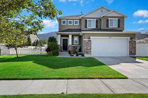 View of front of property with a garage, a mountain view, and a front lawn