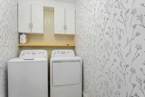 Clothes washing area with washer and dryer and cabinets