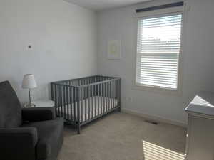 Carpeted bedroom with multiple windows and a crib