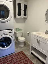 Bathroom featuring stacked washer and dryer, vanity, and toilet