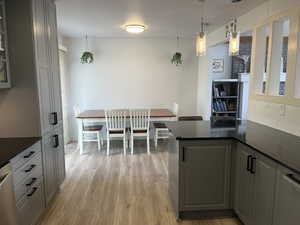 Kitchen featuring gray cabinets, backsplash, light hardwood / wood-style floors, decorative light fixtures, and stainless steel dishwasher