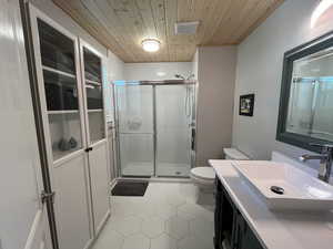 Bathroom featuring toilet, a shower with shower door, wood ceiling, vanity, and tile patterned flooring