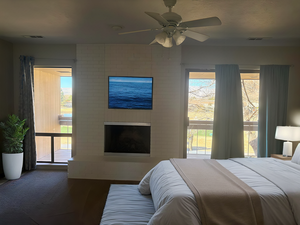 Bedroom featuring hardwood / wood-style flooring, a fireplace, and ceiling fan