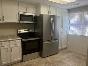 Kitchen featuring stainless steel appliances and white cabinets