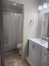 Full bathroom featuring vanity, shower / bath combo, tile patterned floors, and toilet