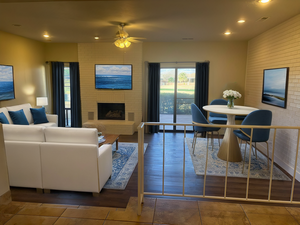 Living room with ceiling fan, a brick fireplace, and dark tile patterned floors