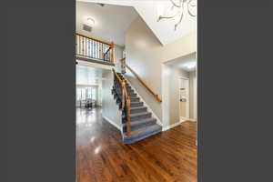 Staircase featuring wood finished floors, a chandelier, and a high ceiling
