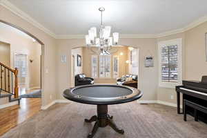 Game room with ornamental molding, carpet, and a chandelier