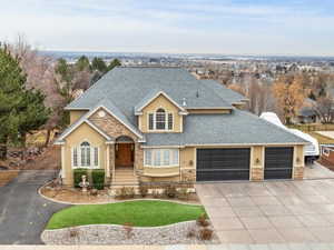 View of front of property featuring a shingled roof, concrete driveway, stone siding, and an attached garage